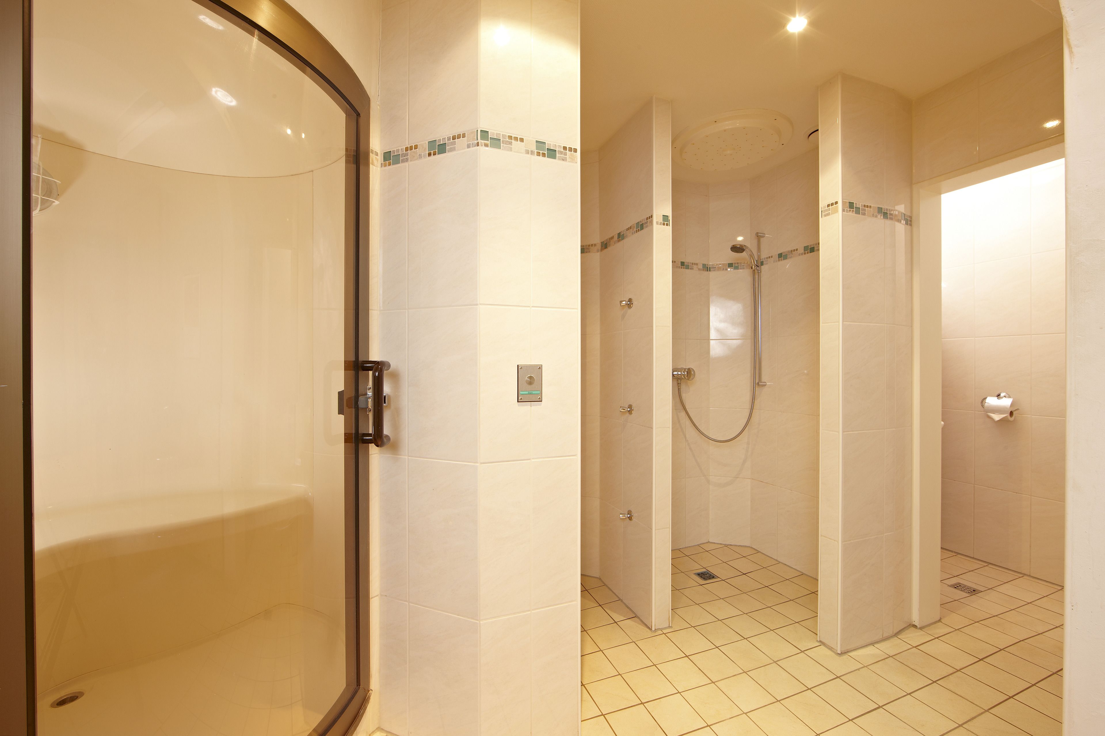 Ein modernes Badezimmer mit einer gläsernen Duschkabine, einer separaten Toilette und einem Fliesenboden.