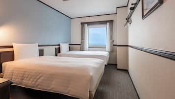 Habitación de hotel con dos camas, ventana con cortinas, cabecero y lámpara de pared.