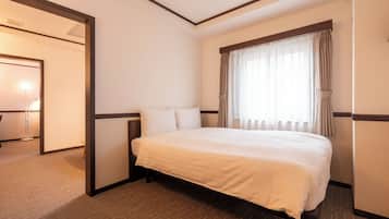 A hotel room with a large bed, a bedside table, a window with curtains, and a door leading to another room.