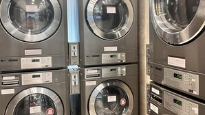 A stack of commercial laundry machines with control panels and labels.
