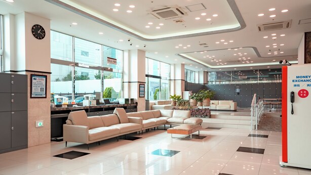 A modern lobby with a cash desk, seating area, and large windows.
