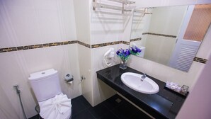 Un baño con inodoro blanco, lavamanos negro y espejo sobre el lavamanos.