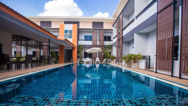 Una piscina con suelo de baldosas, rodeada por un edificio con varios balcones y ventanas.