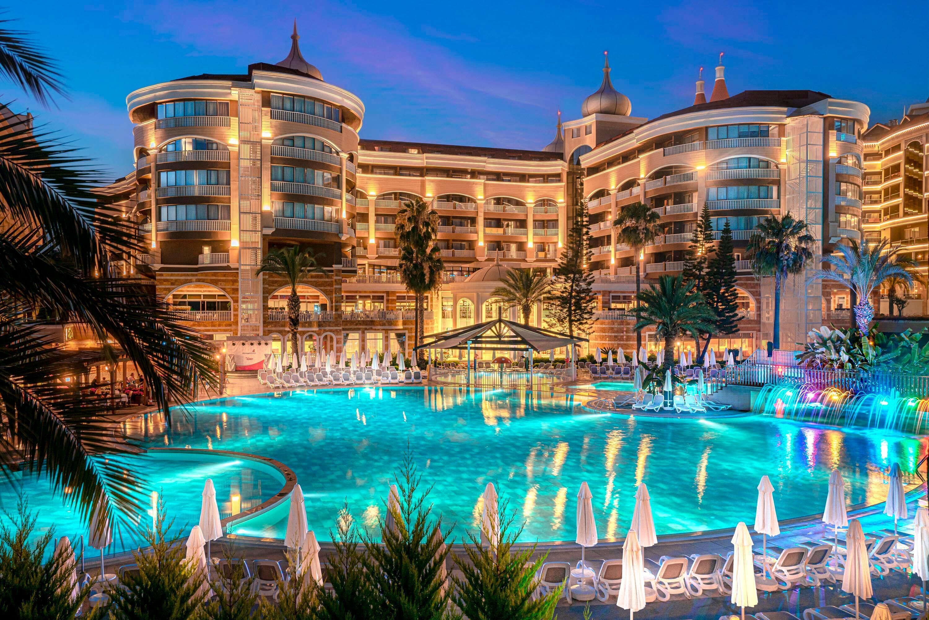 A hotel with a large pool, multiple balconies, and a fountain.