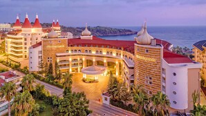 A hotel with a central courtyard, multiple domed structures, and a view of the sea. - Arycanda Kirman Premium - Ultra All Inclusive (Alanya)