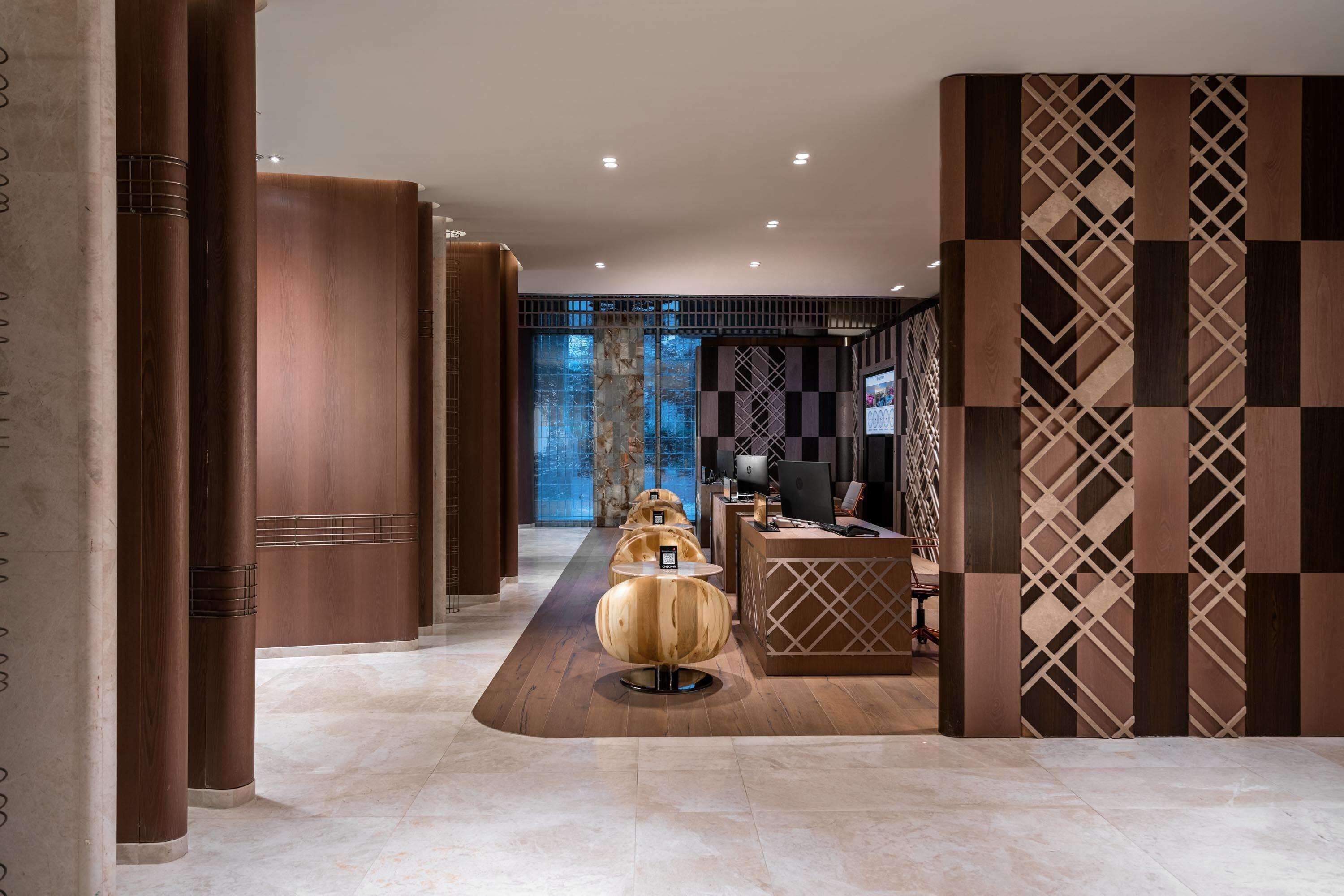 Un moderno vestíbulo con una recepción, un área de asientos esférica y una pared con diseño.