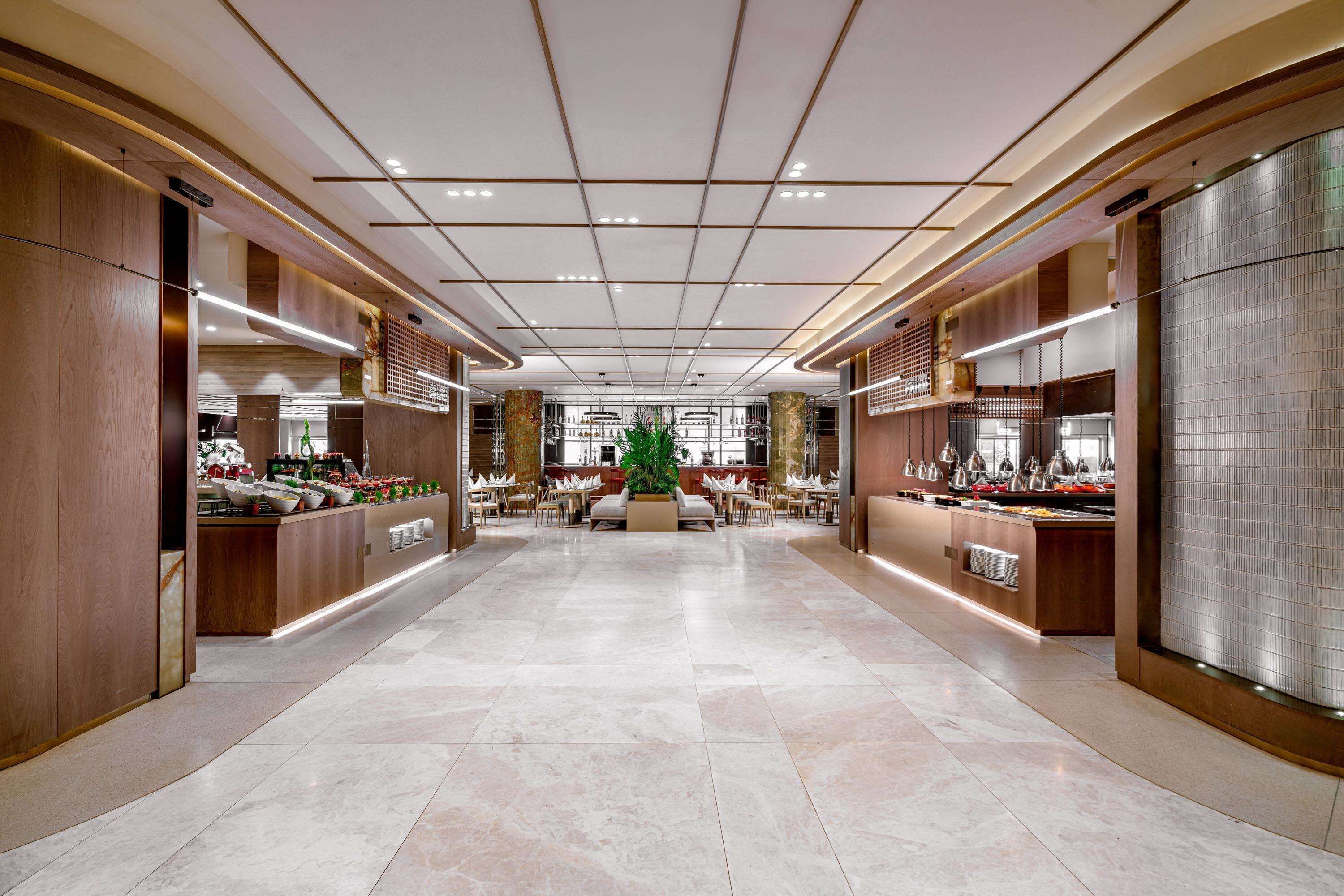 A spacious lobby with a central seating area, multiple counters, and a modern ceiling design.