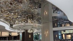 Un restaurant spacieux au décor moderne, avec des luminaires suspendus et un plafond incurvé. Les tables et les chaises sont disposées pour accueillir les clients.