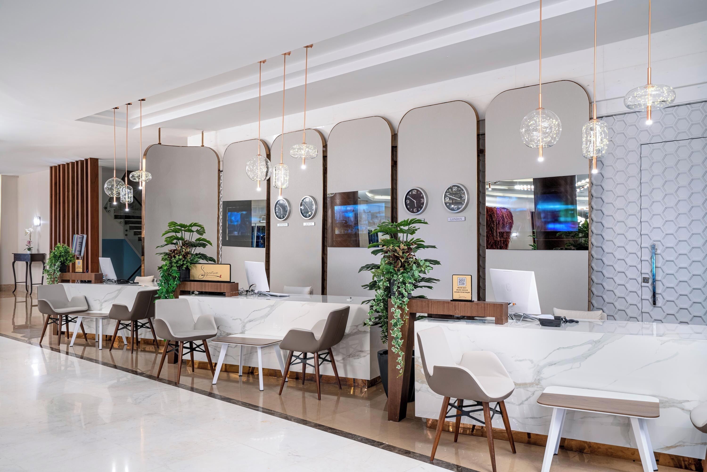 A modern reception area with marble counters, comfortable seating, and decorative plants.
