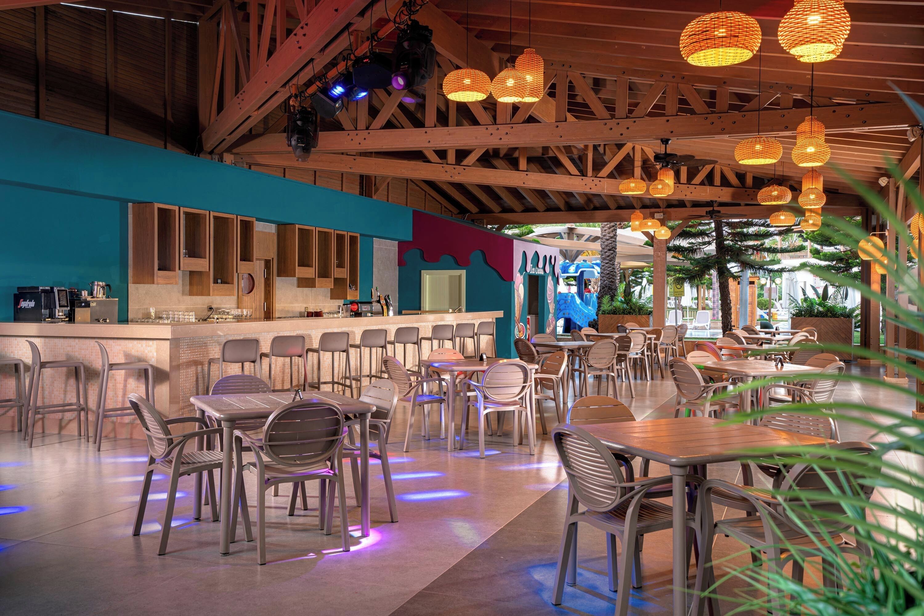 A restaurant with a bar area, wooden ceiling, and hanging lights.