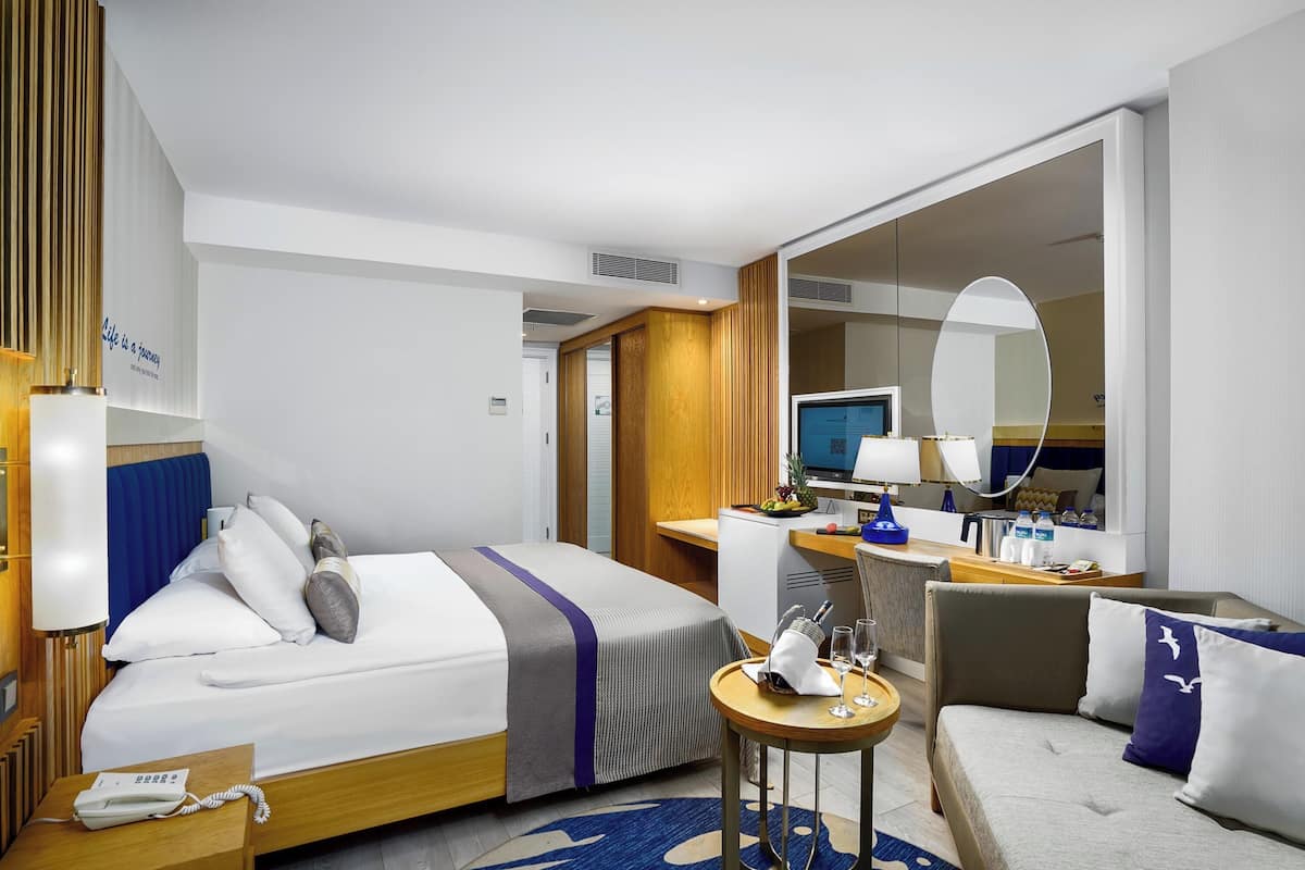 Een hotelkamer met een bed, een bureau, een stoel, een kleine tafel, een spiegel en een televisie.