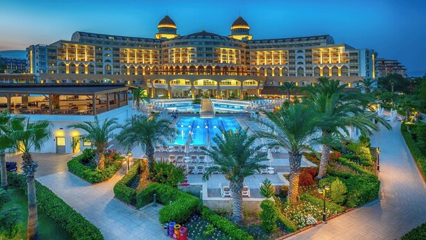 A large, multi-story hotel with a central swimming pool, surrounded by palm trees and well-maintained gardens. - Sidemarin Kirman Premium - Ultra All Inclusive (Manavgat)