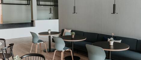 A modern interior with round tables, chairs, and a sofa.