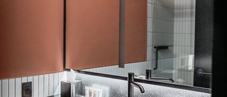 Une salle de bain moderne avec un grand miroir, un lavabo rond et un distributeur de serviettes.