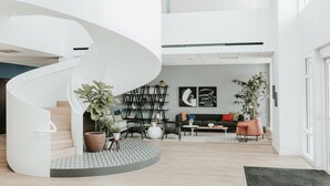 A modern interior with a spiral staircase, a seating area with a sofa and chairs, and a bookshelf.
