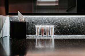 A black tissue box and four tubes of hair care products on a speckled countertop.