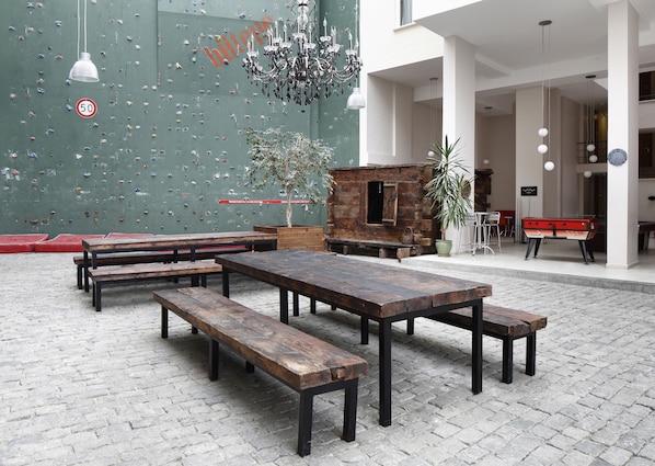 A spacious indoor area with climbing walls, wooden benches, a billiards table, and a rustic fireplace.