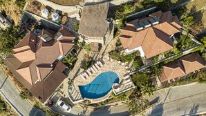 An aerial view of a residential area with multiple houses, a swimming pool, and a curved road. - Les Terrasses De Selimiye (Marmaris)