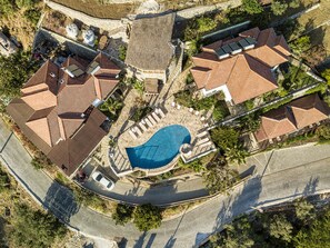 An aerial view of a residential area with multiple houses, a swimming pool, and a curved road. - Les Terrasses De Selimiye (Marmaris)
