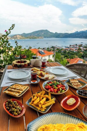 A table set with various dishes and a view of a lake and mountains. - Les Terrasses De Selimiye (Marmaris)