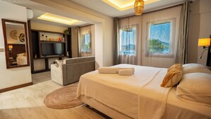 A hotel room with a bed, a sofa, a TV, a window with a view, and a ceiling light. - Les Terrasses De Selimiye (Marmaris)