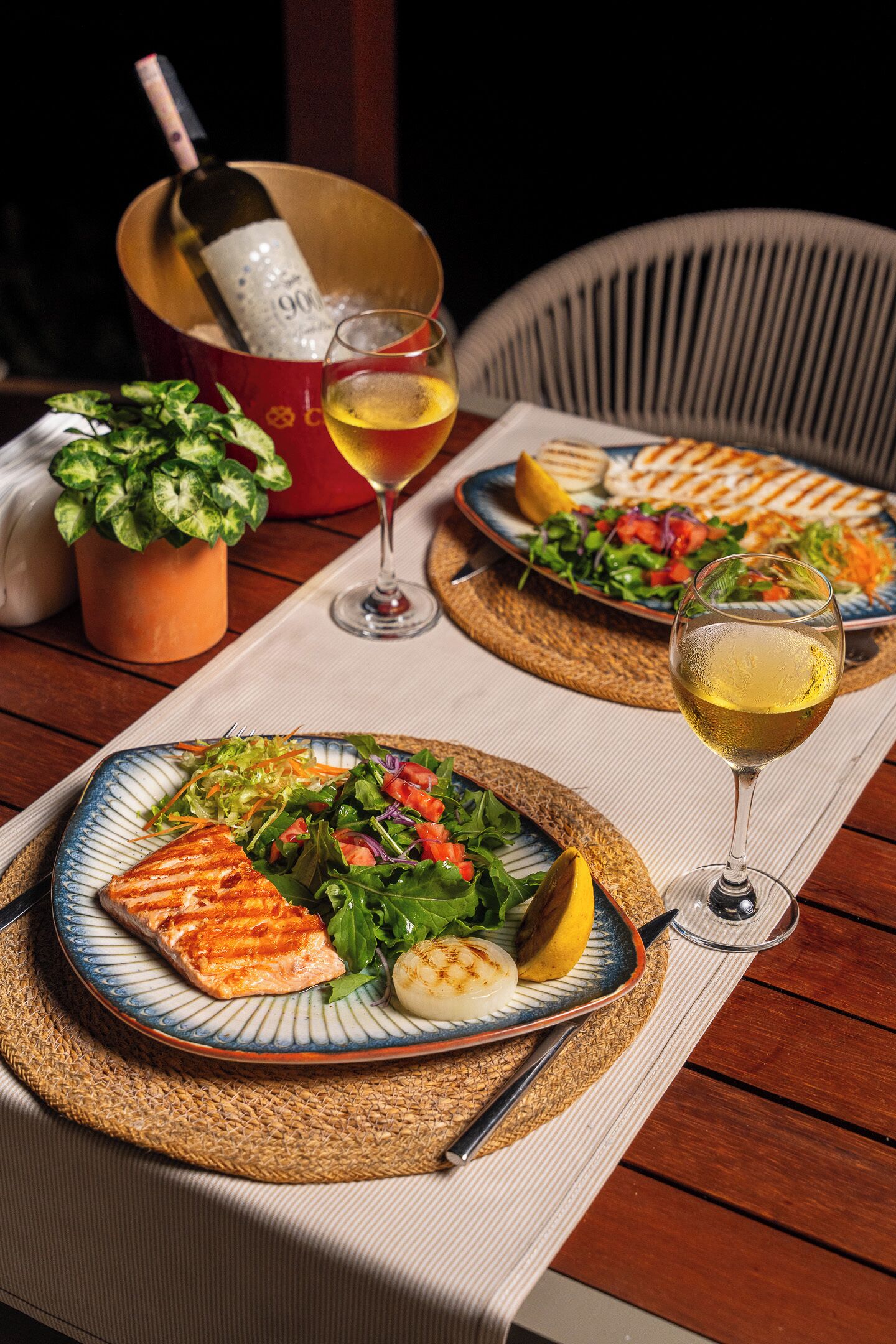 Une table à manger avec des assiettes remplies de nourriture, une bouteille de vin et un verre de vin.