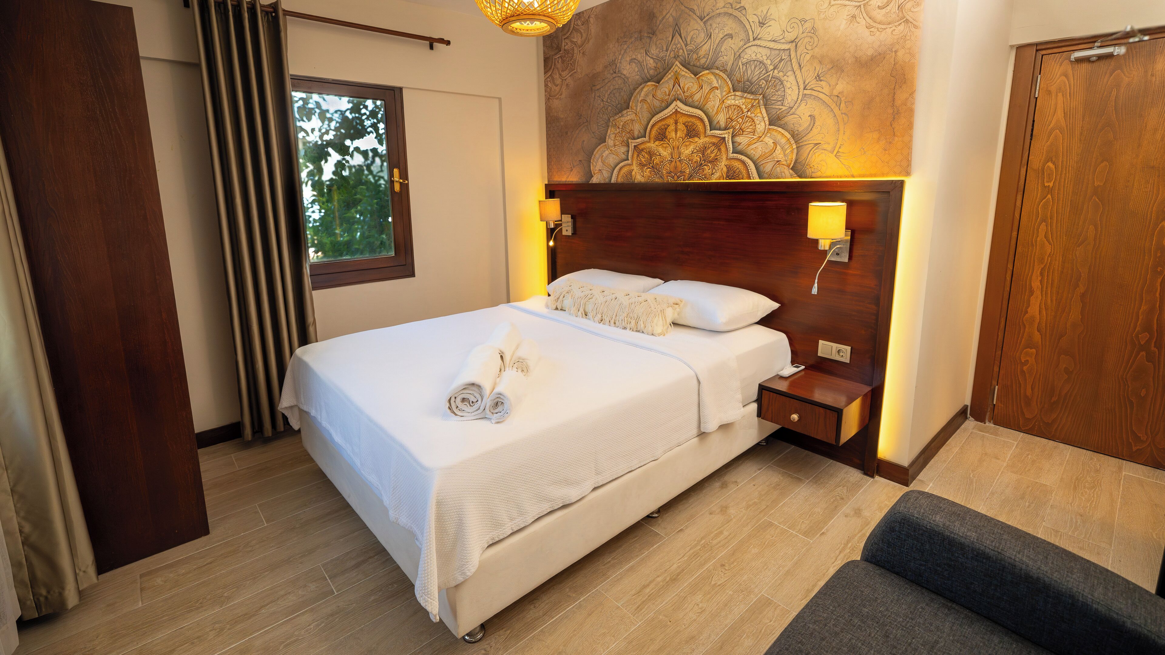 A hotel room with a bed, a nightstand, a lamp, and a wall with a decorative pattern.