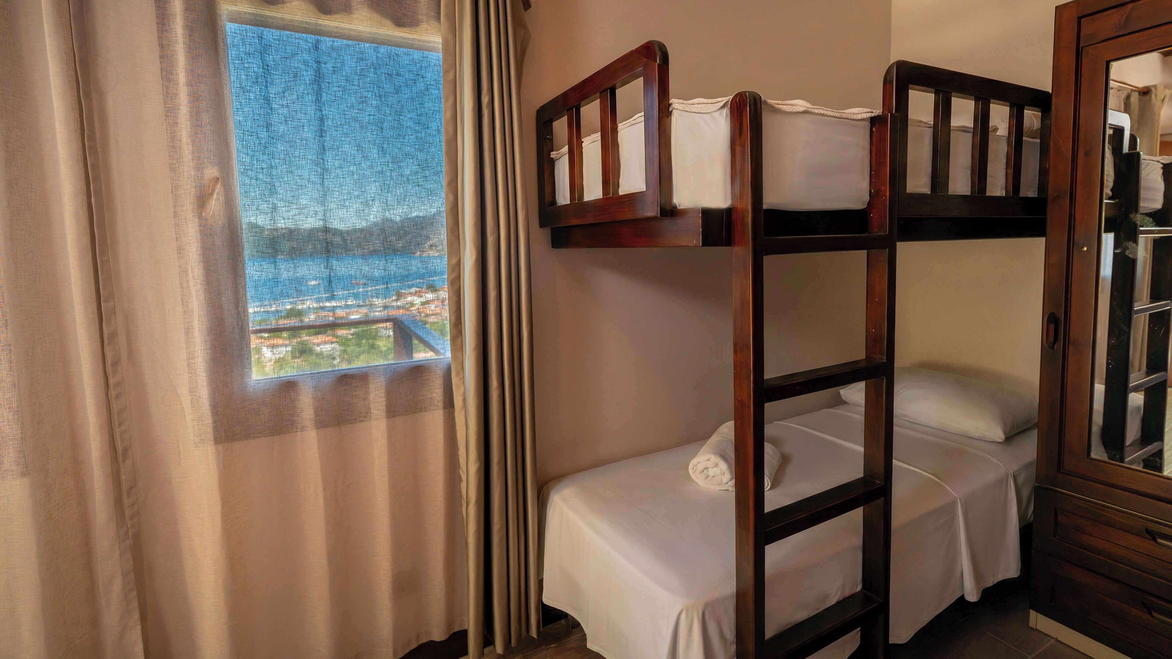A bunk bed room with a window overlooking a cityscape.