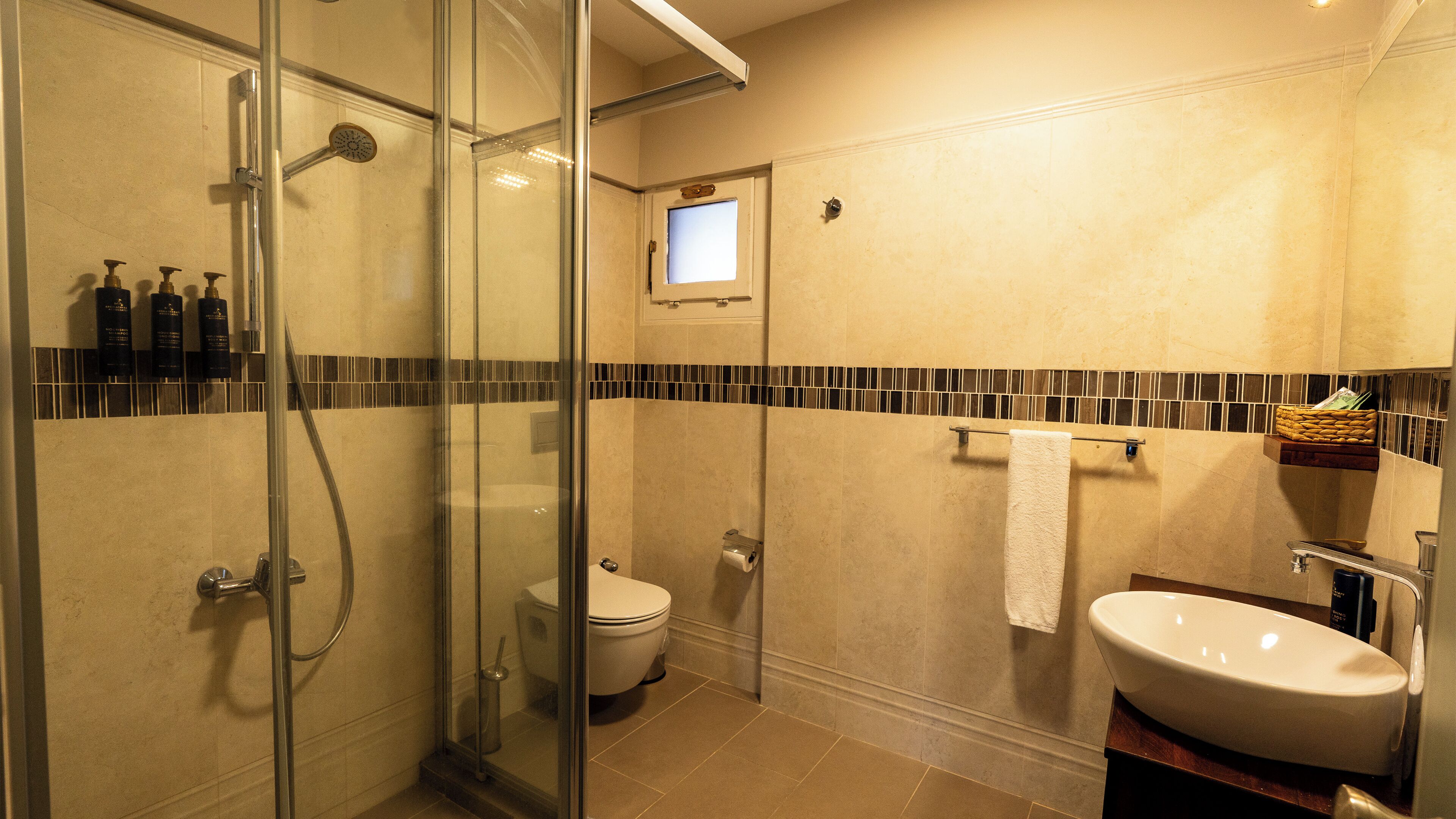 A bathroom with a glass-enclosed shower, a toilet, a sink, and a towel rack.