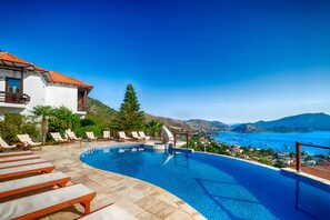 Una piscina al aire libre, sombrillas, sillones reclinables de piscina