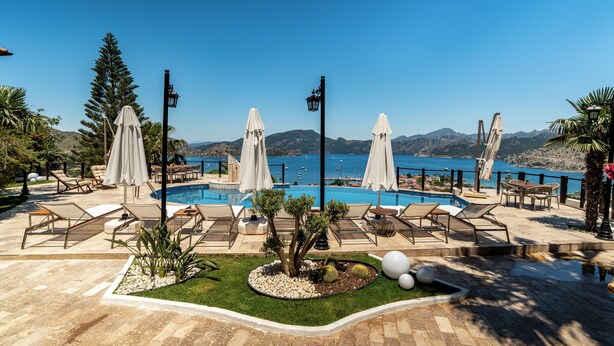 A poolside area with lounge chairs, umbrellas, and a view of the sea. - Les Terrasses De Selimiye (Marmaris)