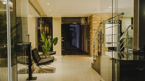 La entrada del Hotel YVERA Cataratas, con un puerta de vidrio, un felpudo negro con el nombre del hotel, y una escalera que conduce al interior.