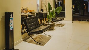 Un vestíbulo moderno con zona de estar, mostrador de recepción y una pared divisoria de vidrio.
