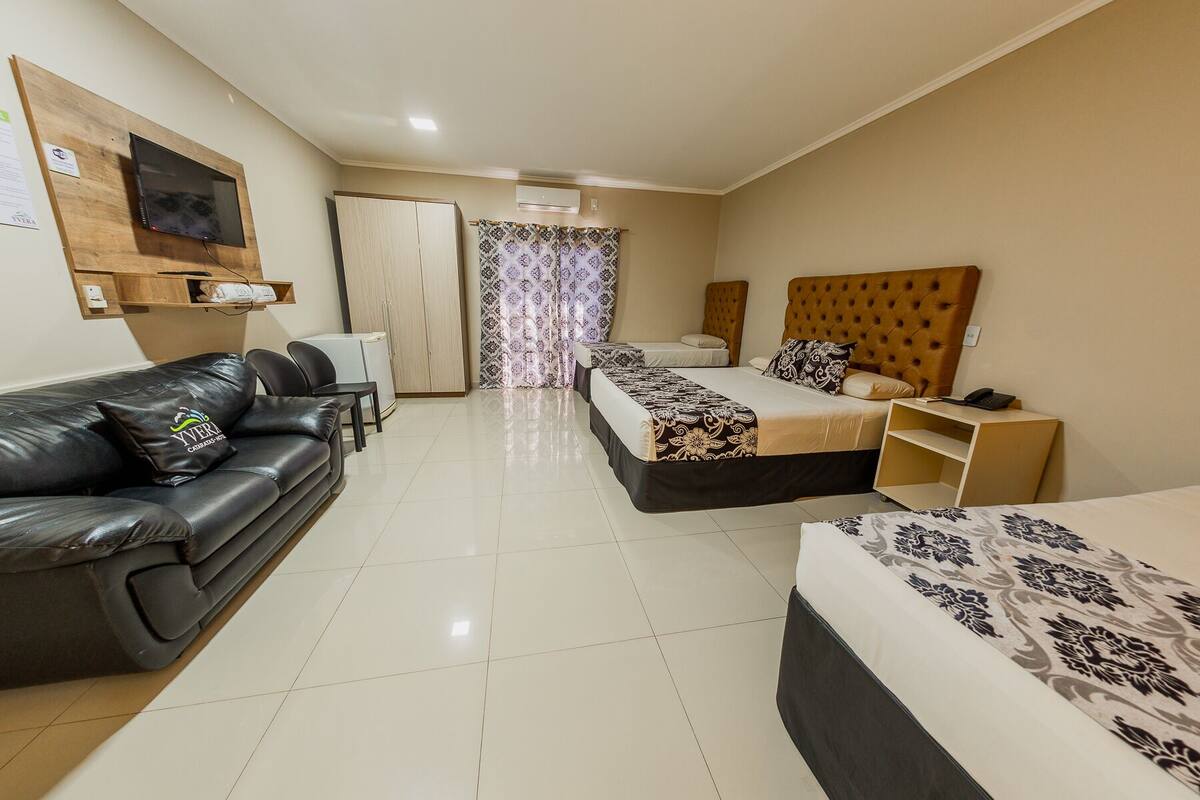 Habitación de hotel con cama, sofá, escritorio y televisor.