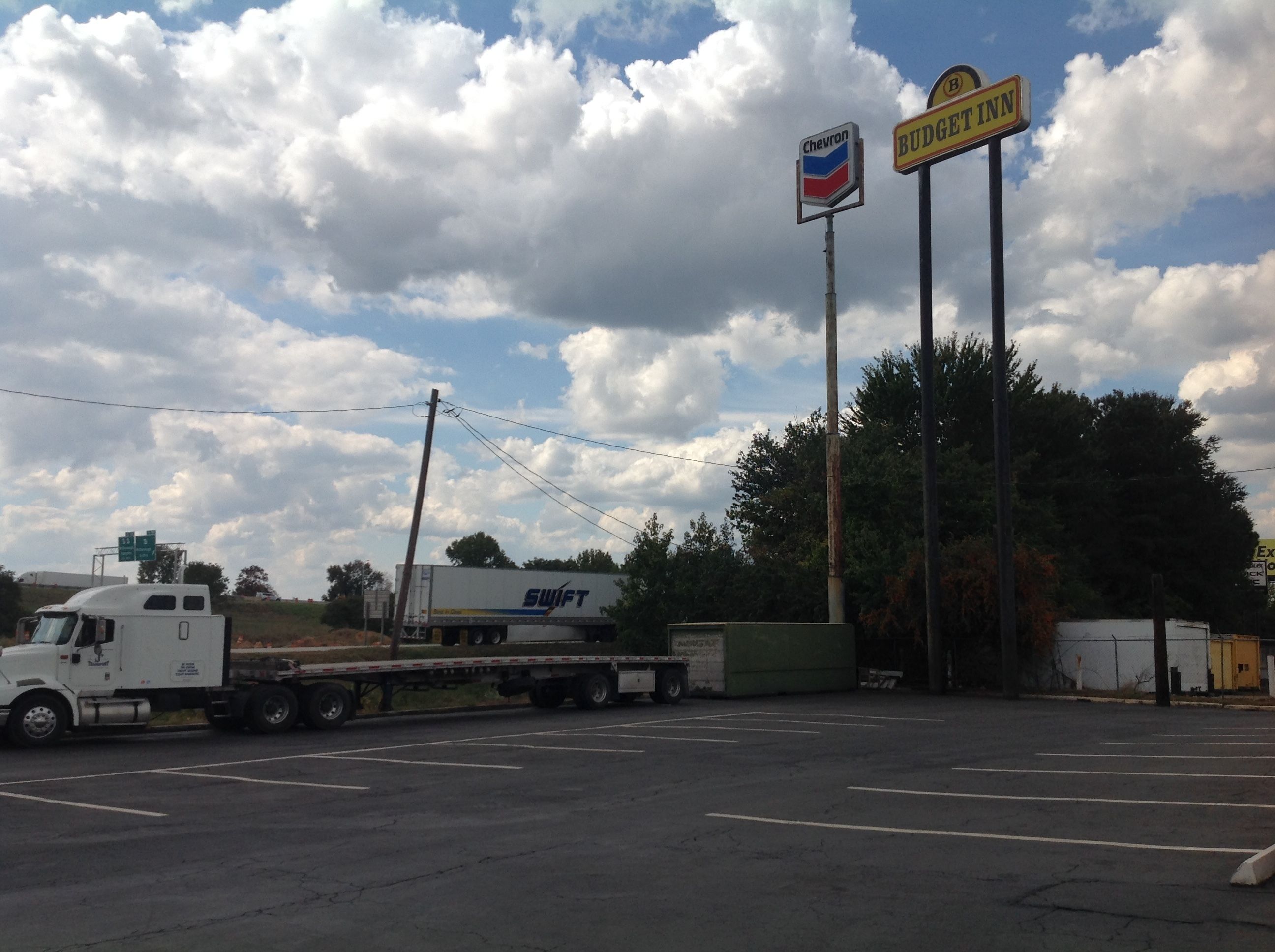 A parking lot with a Chevron gas station and a Budget Inn sign.