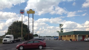 A parking lot with a Budget Inn sign, a Chevron gas station, and a Chevrolet dealership. - Budget Inn (McDonough)