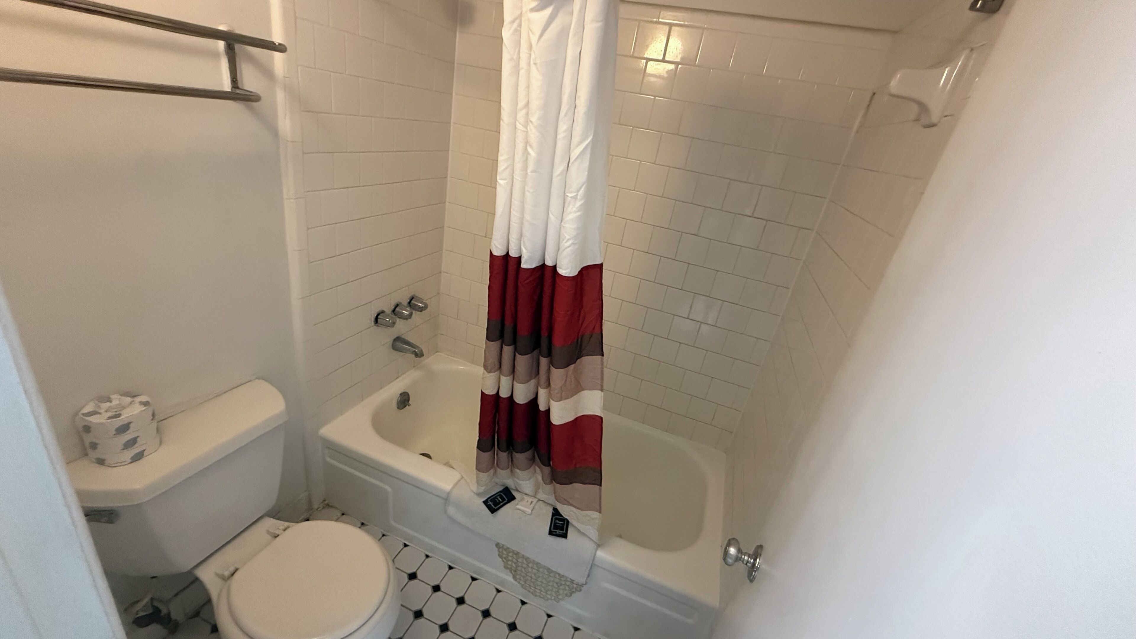 Un baño con inodoro, bañera y cortina de ducha.