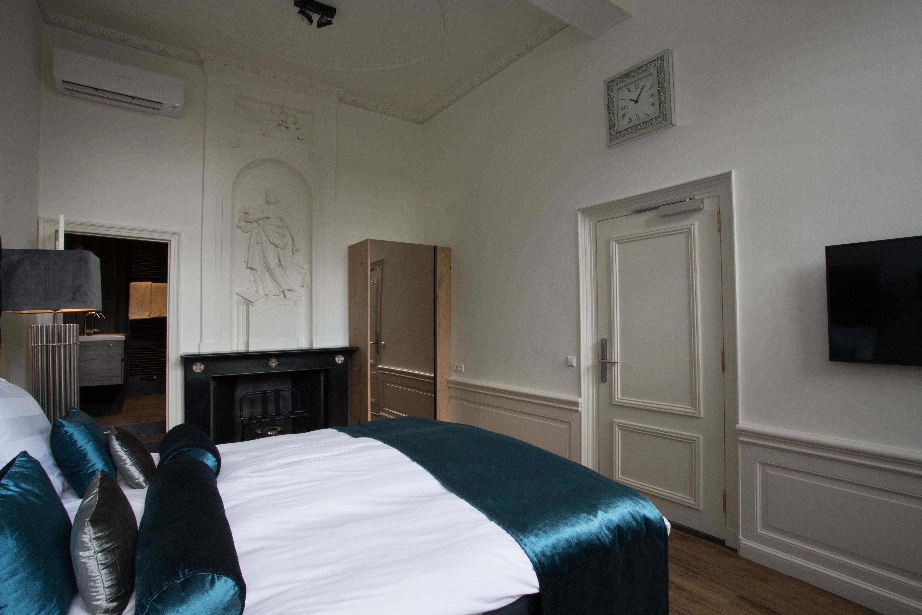 Een hotelkamer met een bed, een televisie, een open haard en een deur.