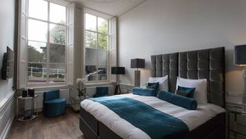 Une chambre avec un grand lit, une fenêtre, un radiateur et une chaise.