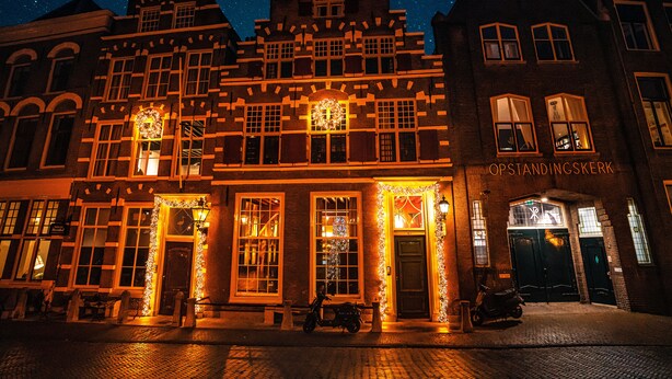 Un edificio histórico con arquitectura tradicional, con múltiples ventanas y un letrero que dice "OPSTANDINGSKERK".