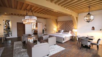 A spacious bedroom with a large bed, a sitting area with sofas, and a dining table.