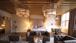 Un dormitorio espacioso con una cama grande, dos sofás, una mesa de centro con velas y un candelabro.