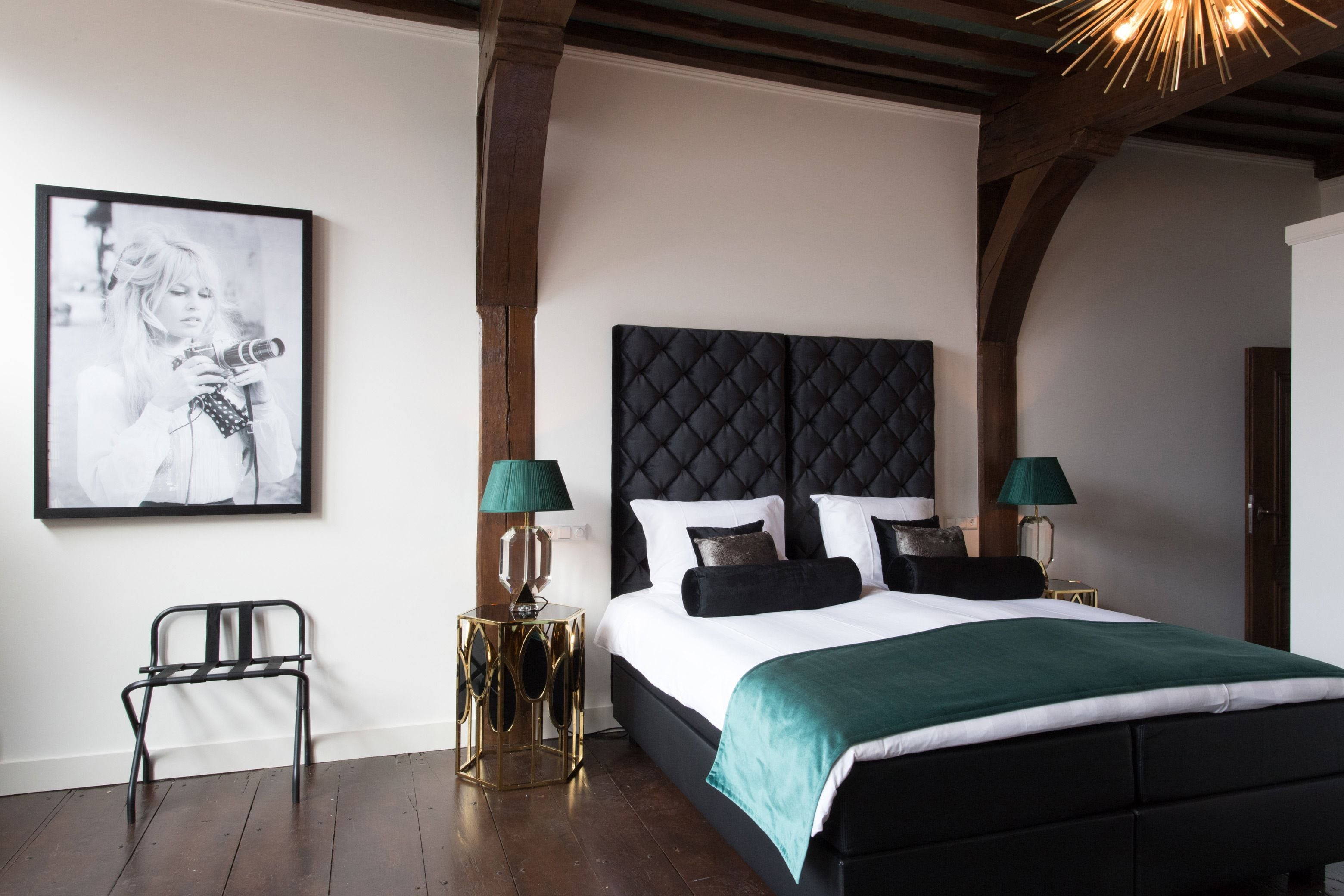 A bedroom with a large bed, two bedside tables, a framed picture on the wall, and a chair.