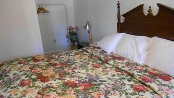 Un dormitorio con colcha estampada, cabecero de madera y pared blanca.