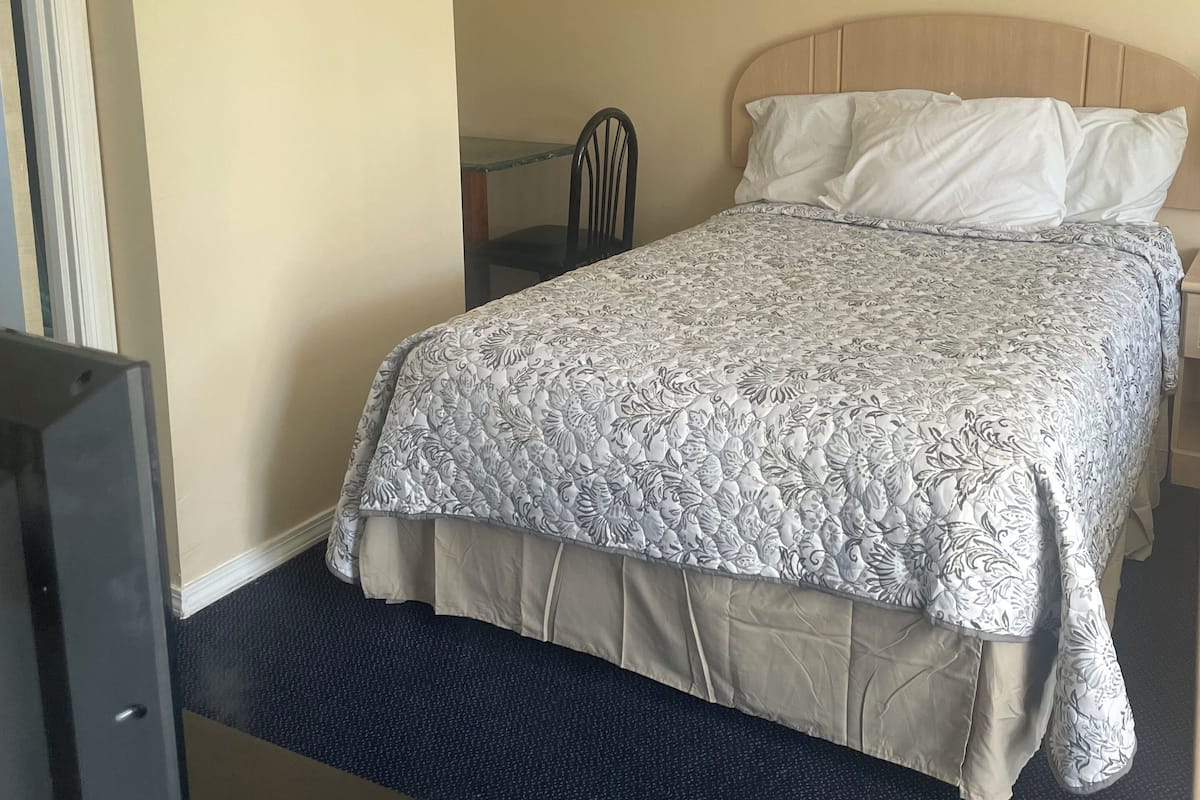 Una habitación de hotel con una cama, una silla y un televisor.