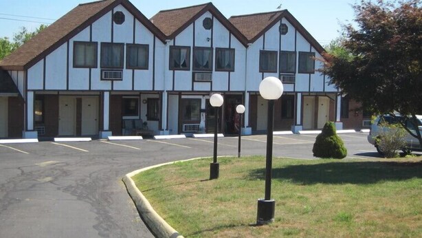 A two-story motel with a symmetrical facade, multiple windows, and a parking lot in front. - Lamplighter Motel - Clinton, Connecticut (Clinton)