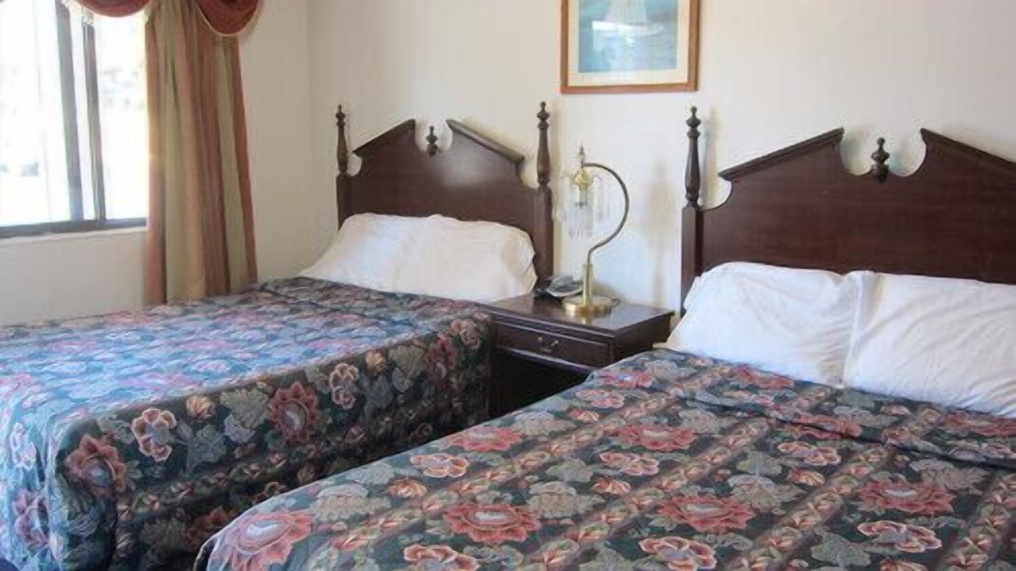 A double room with two beds, each with floral bedding and wooden headboards.