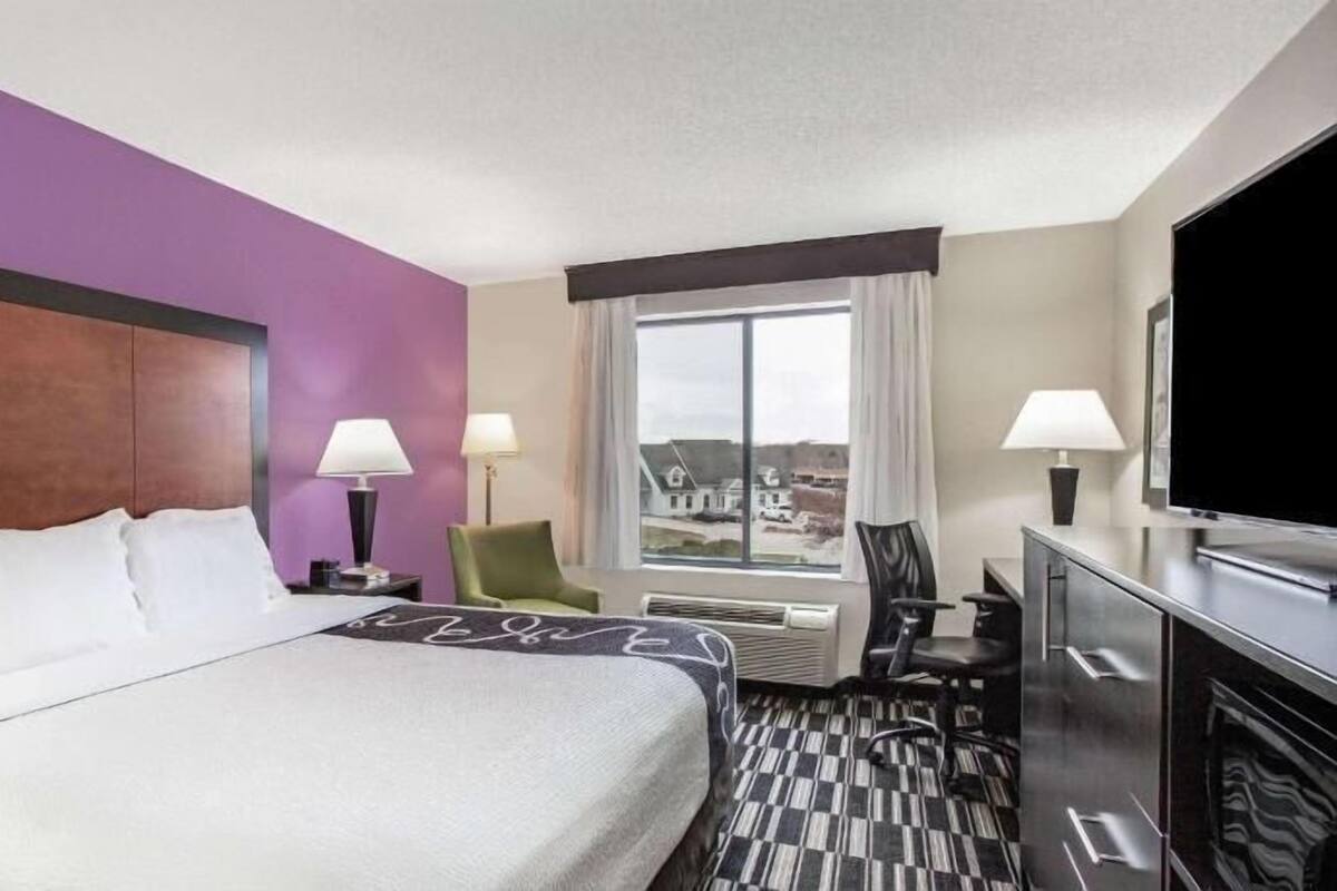Ein Hotelzimmer mit einem großen Bett, zwei Sesseln, einem Schreibtisch, einem Fernseher und einem Fenster mit Blick.