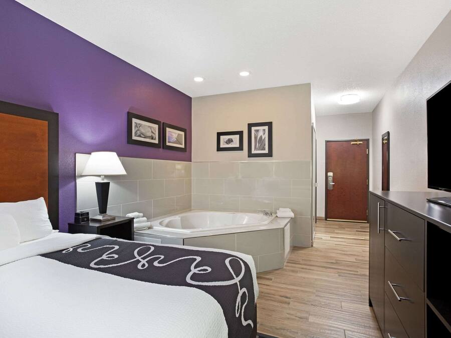 Ein Hotelzimmer mit Bett, Badezimmer mit Badewanne, Fernseher und Schreibtisch mit Lampe.
