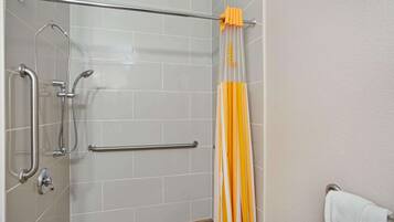 Zona de ducha con barras de apoyo, un perchero y una cortina de baño a rayas.